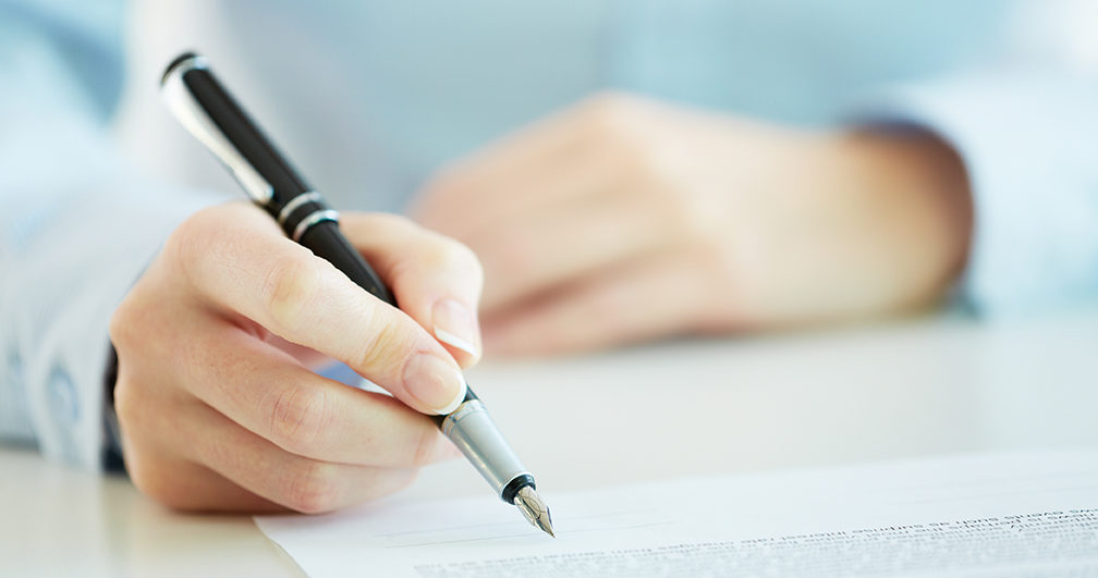 Henkilö allekirjoittamassa sopimuspaperia